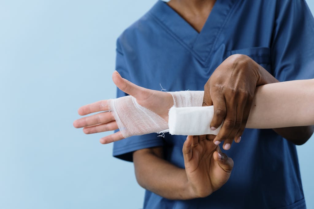 A medical professional carefully wrapping a bandage around an injured person's hand.